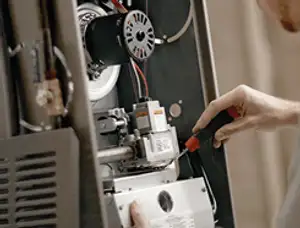 Furnace repair technician inspecting internal components and wiring in Saint Louis, MO