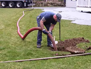 Septic pumping technician servicing a residential septic tank with a vacuum hose in Saint Louis, MO