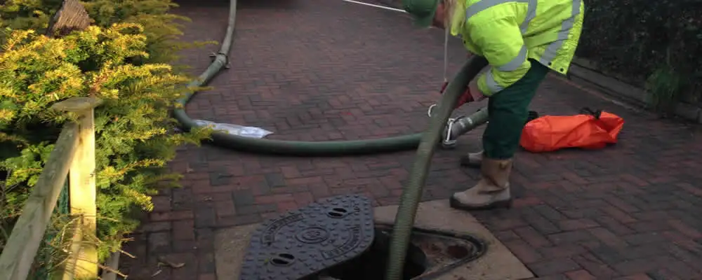 Septic tank cleaning technician servicing a septic tank with a vacuum hose in Saint Louis, MO