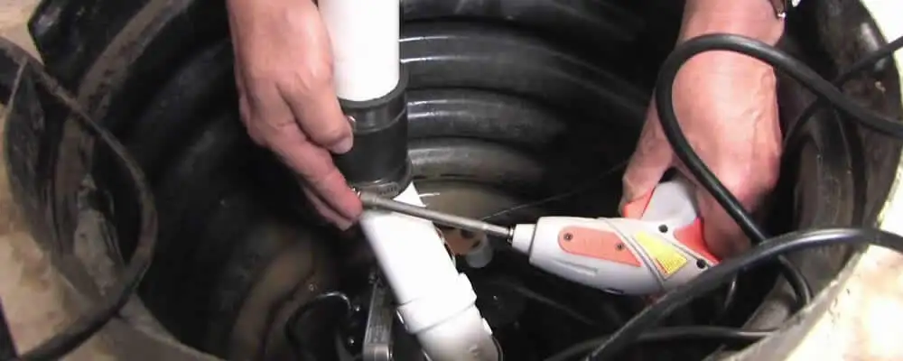 Sump pump installation technician connecting PVC discharge piping in Saint Louis, MO