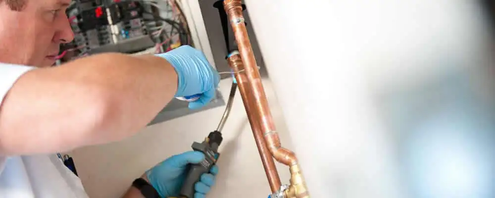 Water heater repair technician testing copper pipe connections and controls in Saint Louis, MO